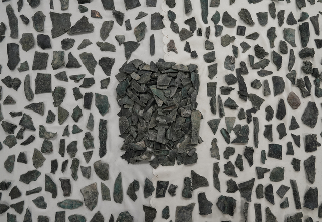 A detailed display of bronze statue fragments carefully organized for analysis, showcasing the intricate work of ancient artisans.