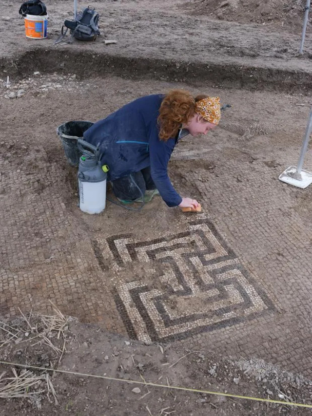 An archaeologist carefully cleans a Roman mosaic, revealing the vibrant artistry preserved for centuries. (Credit: Teffont Archaeology)