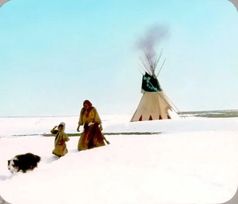 A Blackfeet family braves the snowy prairie, their resilience evident in this early 1900s photograph.