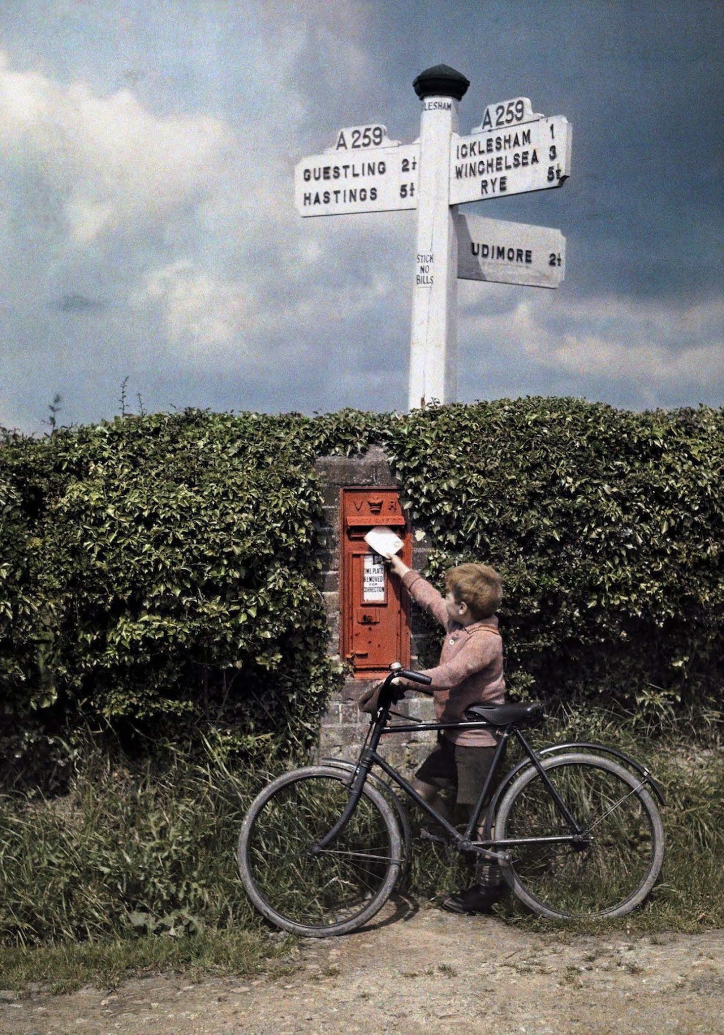 A Child’s First Letter – A little boy posts a letter in a countryside hedgerow in Sussex, a charming glimpse into everyday English life.