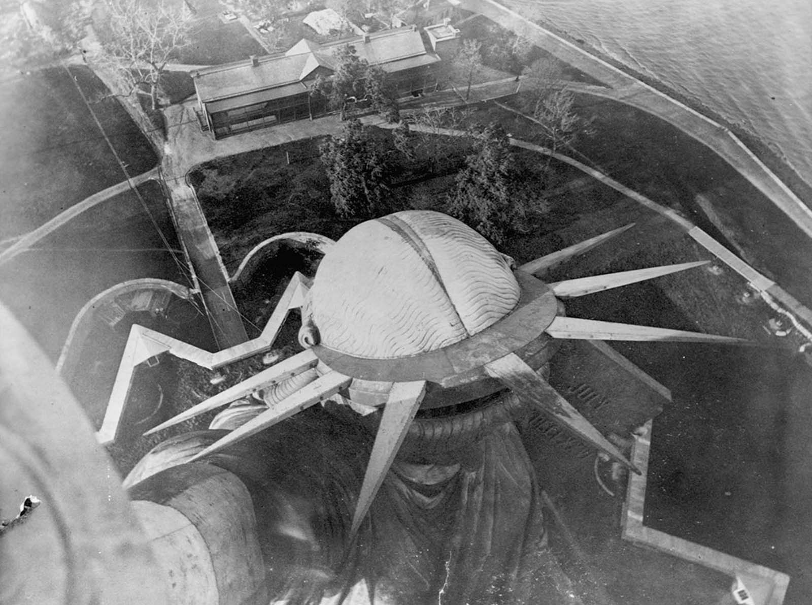 A breathtaking bird’s-eye view of the Statue of Liberty from its torch, circa 1890, capturing its commanding presence over New York Harbor.