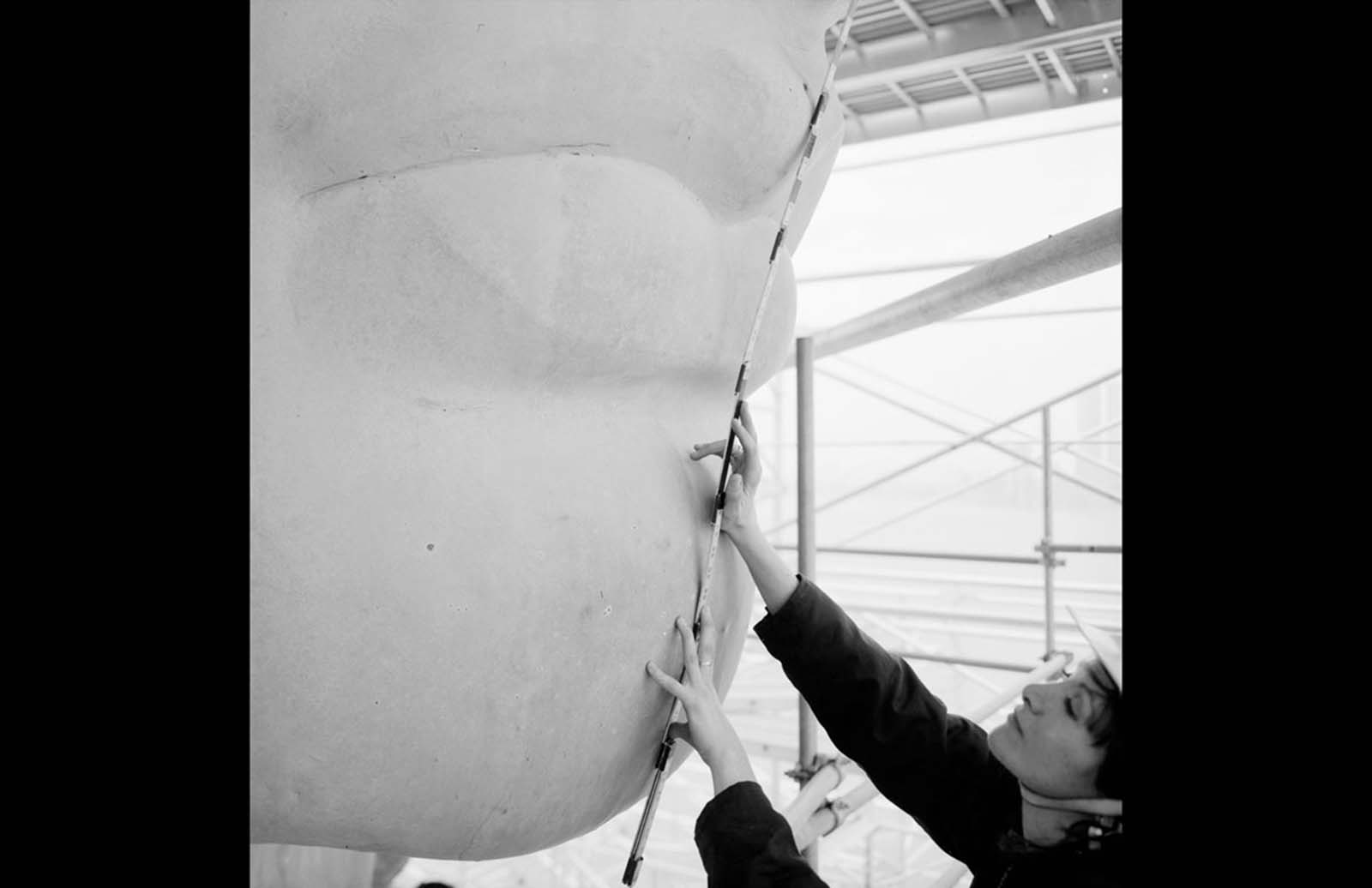 A close-up of the Statue of Liberty’s nose and mouth during its 1985 restoration, with worker Isabel Hill holding a scale stick to measure its dimensions.