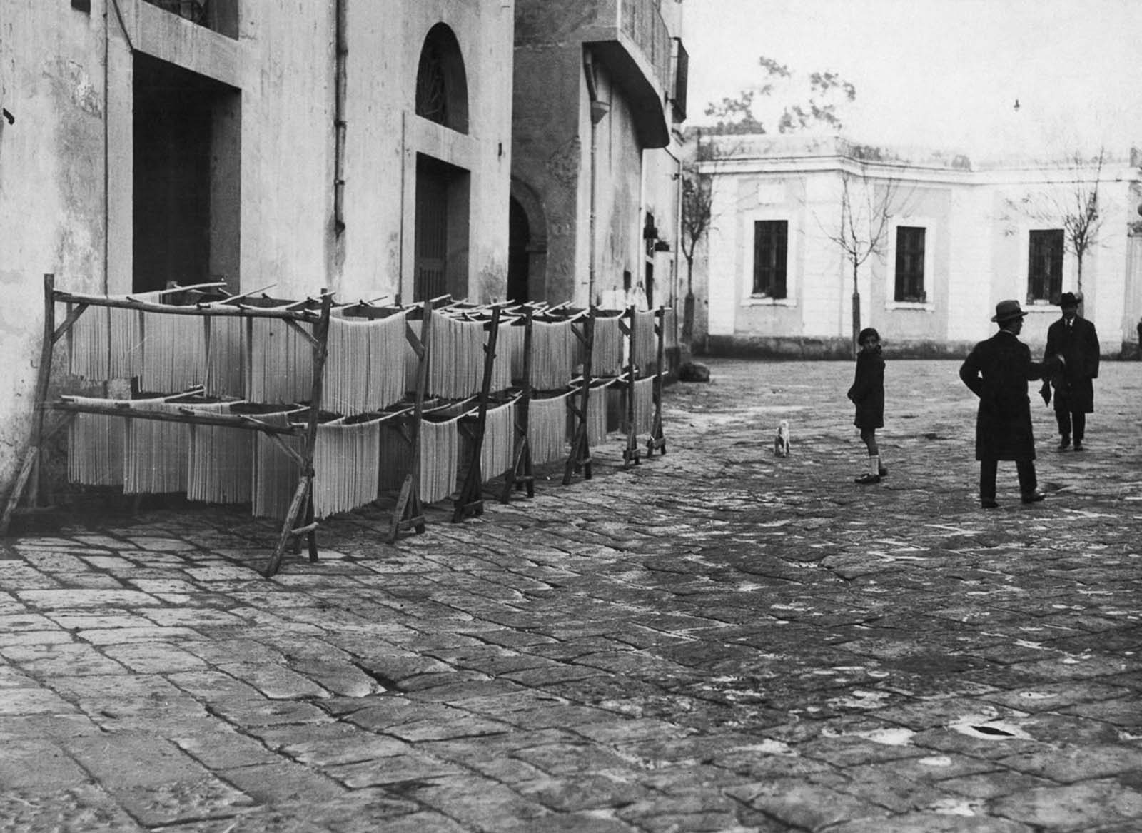 A glimpse of Naples' pasta production, where drying noodles line the streets. 1925.