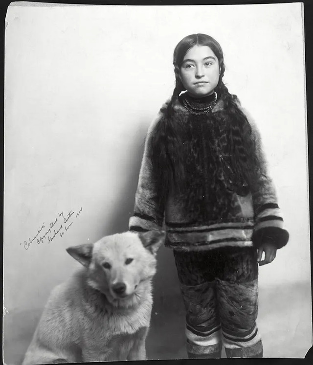 A portrait of Nancy Columbia, an Inuit girl, with her dog, captured in 1904 by the Gerhard Sisters.