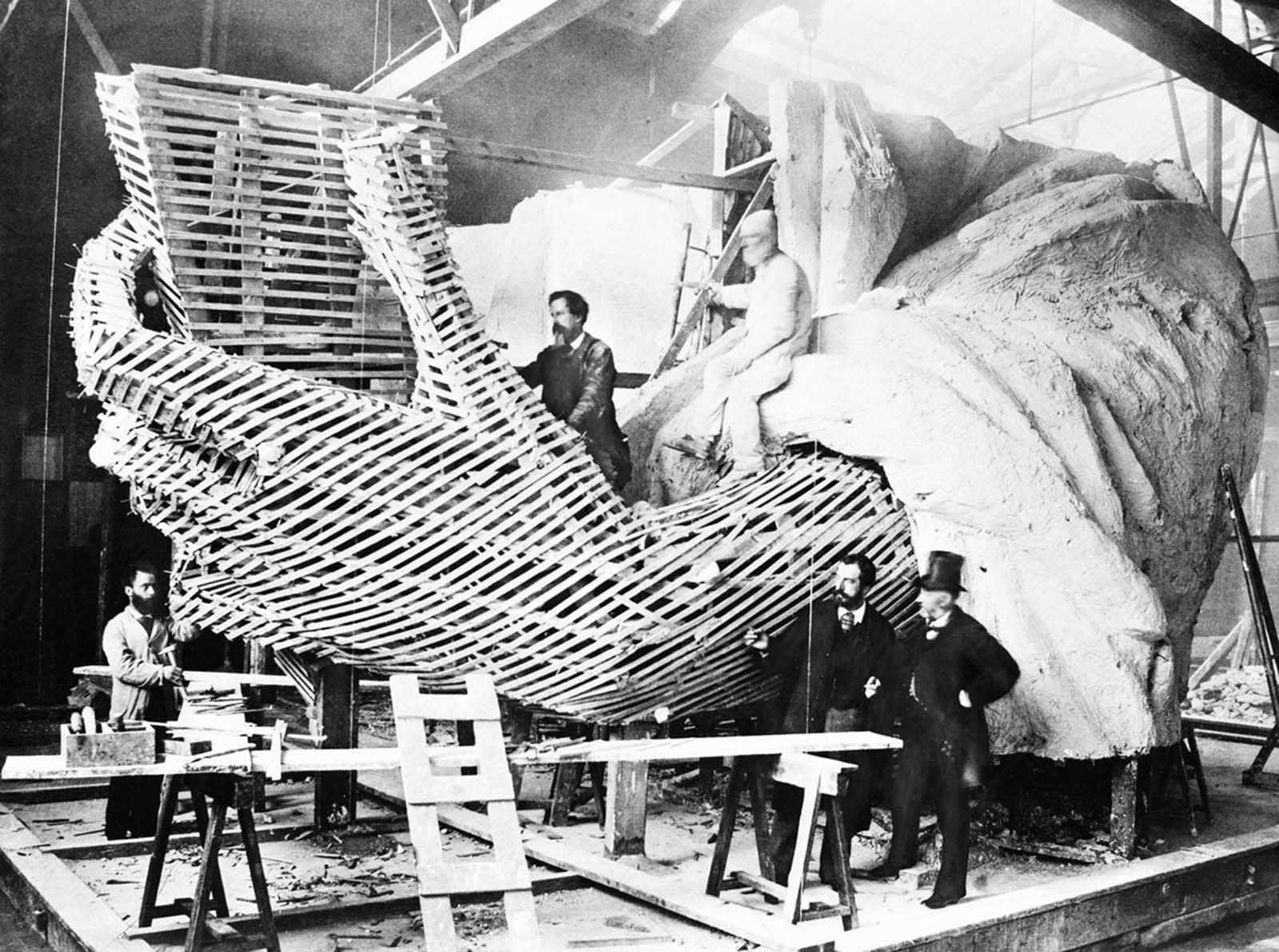 A rare 1875 photograph of Frédéric-Auguste Bartholdi, creator of the Statue of Liberty, seen with a visitor while the statue was still being constructed inside a Paris studio.