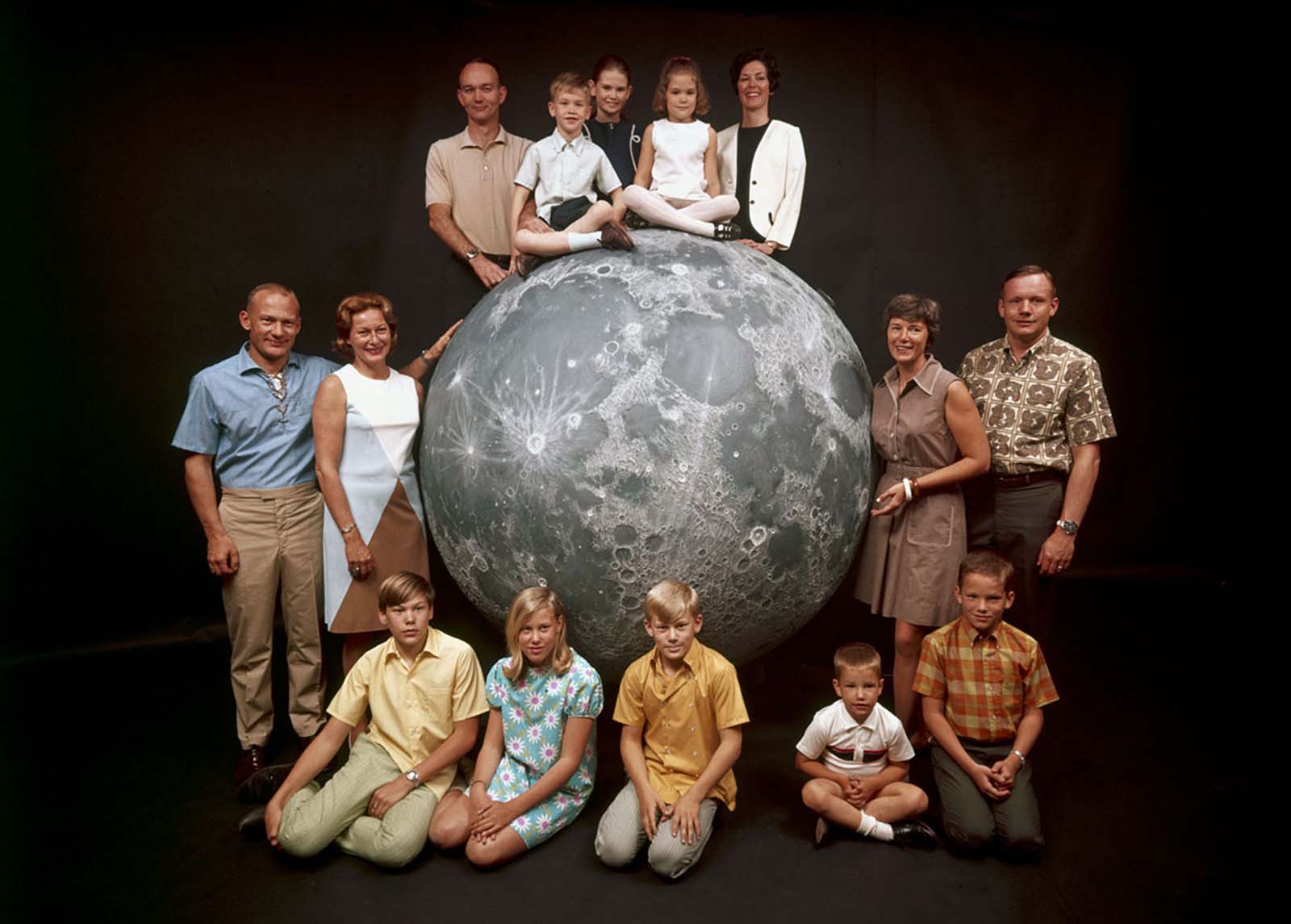 A rare group portrait of the Apollo 11 astronauts and their families gathered around a model of the moon in March 1969, celebrating the journey ahead.