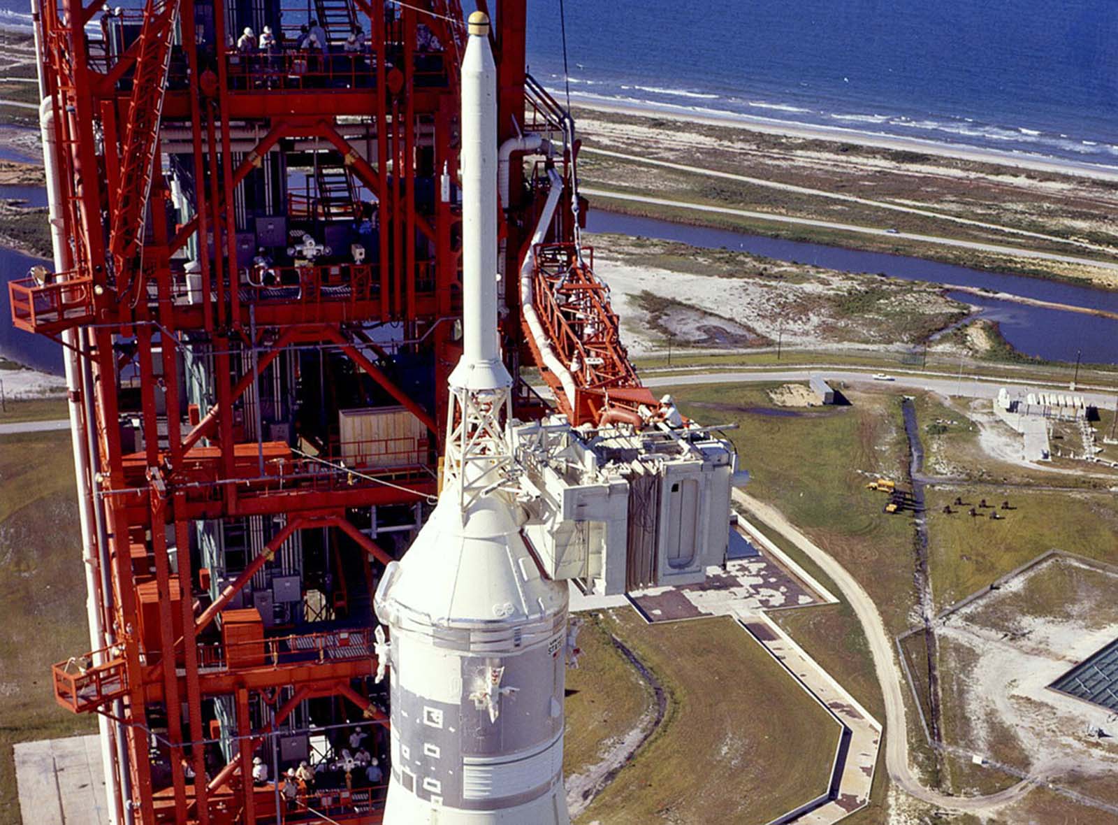 A technician works atop the white room, the final entryway for astronauts before boarding their spacecraft, while Saturn V looms on the launchpad.