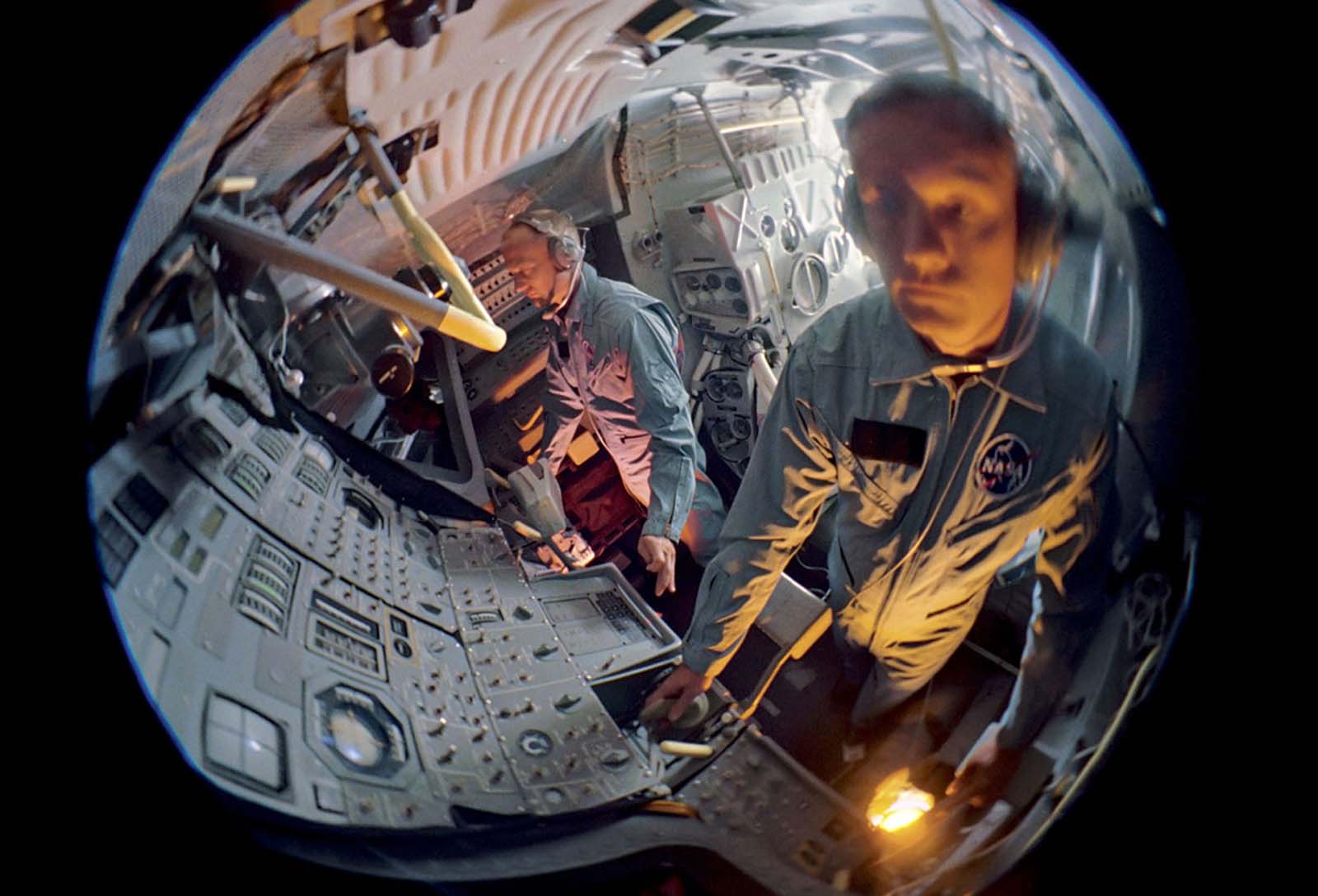 A wide-angle shot captures Buzz Aldrin and Neil Armstrong training inside a mock lunar module, refining their moonwalking techniques.