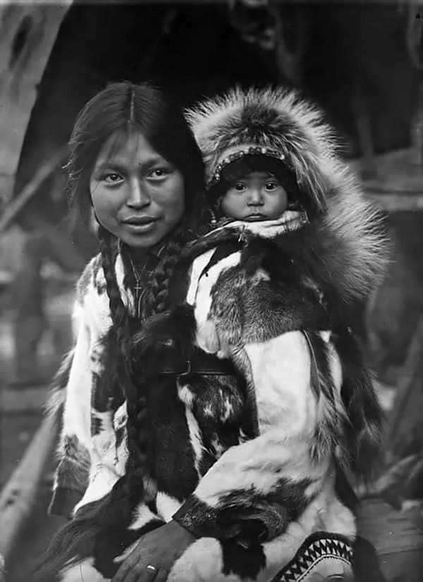 Another view of the King Island Inuit woman, wearing a cross and carrying her child on her back, taken in Alaska between 1915 and 1925.