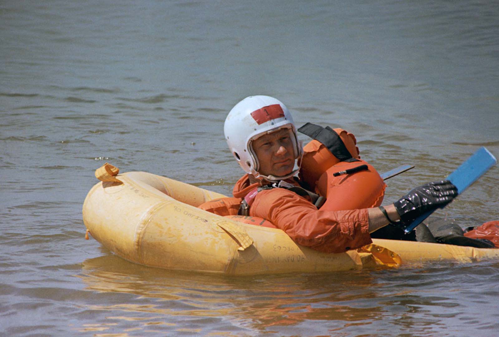 Buzz Aldrin paddles ashore in a one-man life raft during survival training at Lake Texoma, part of Apollo 11’s rigorous preparation.