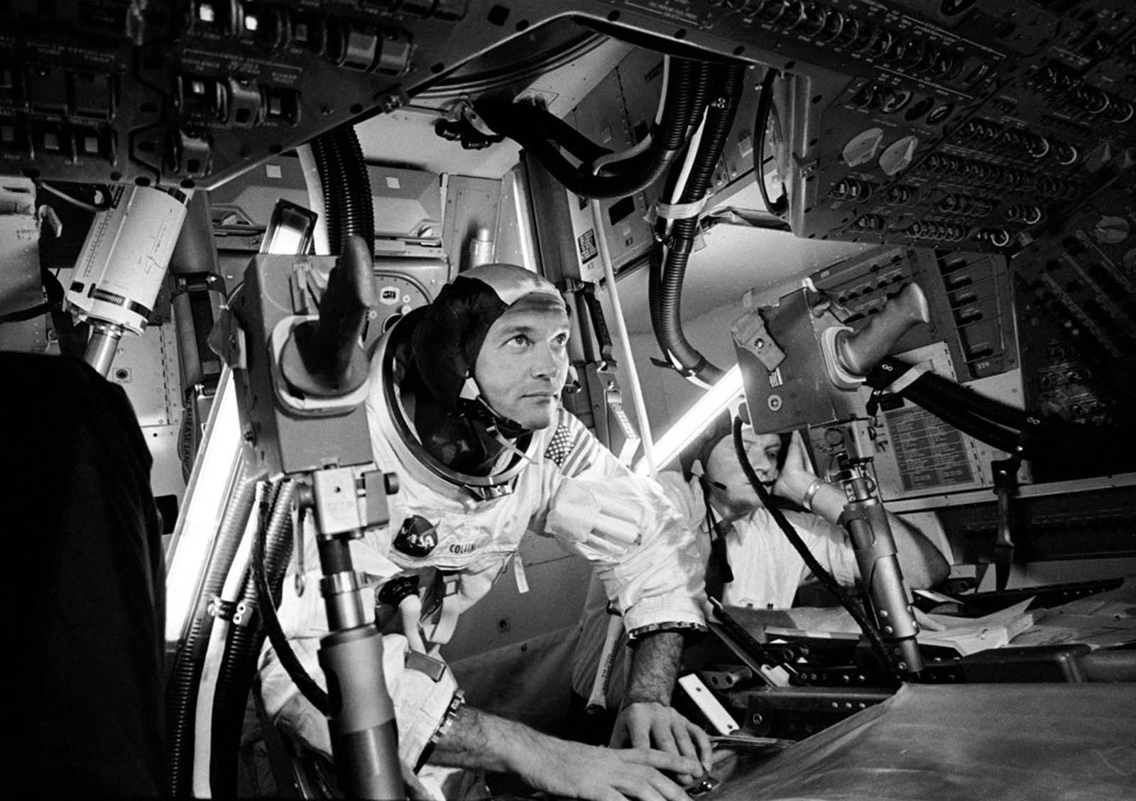 Command Module Pilot Michael Collins sharpens his skills inside a high-tech Apollo 11 simulator.