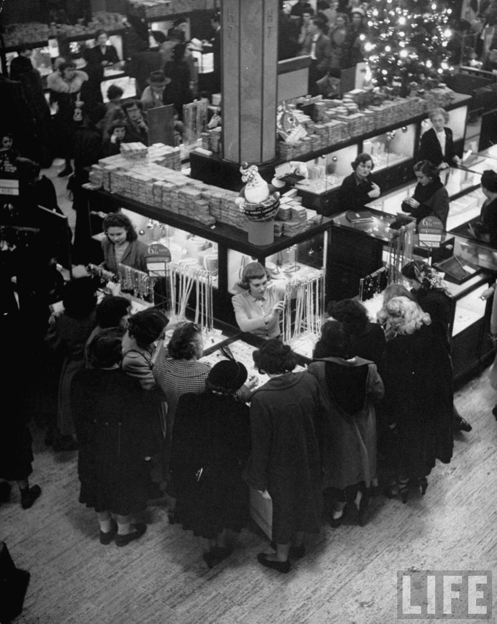 A bustling scene at Macy’s in 1948, with customers gathered around a jewelry display during the holiday season