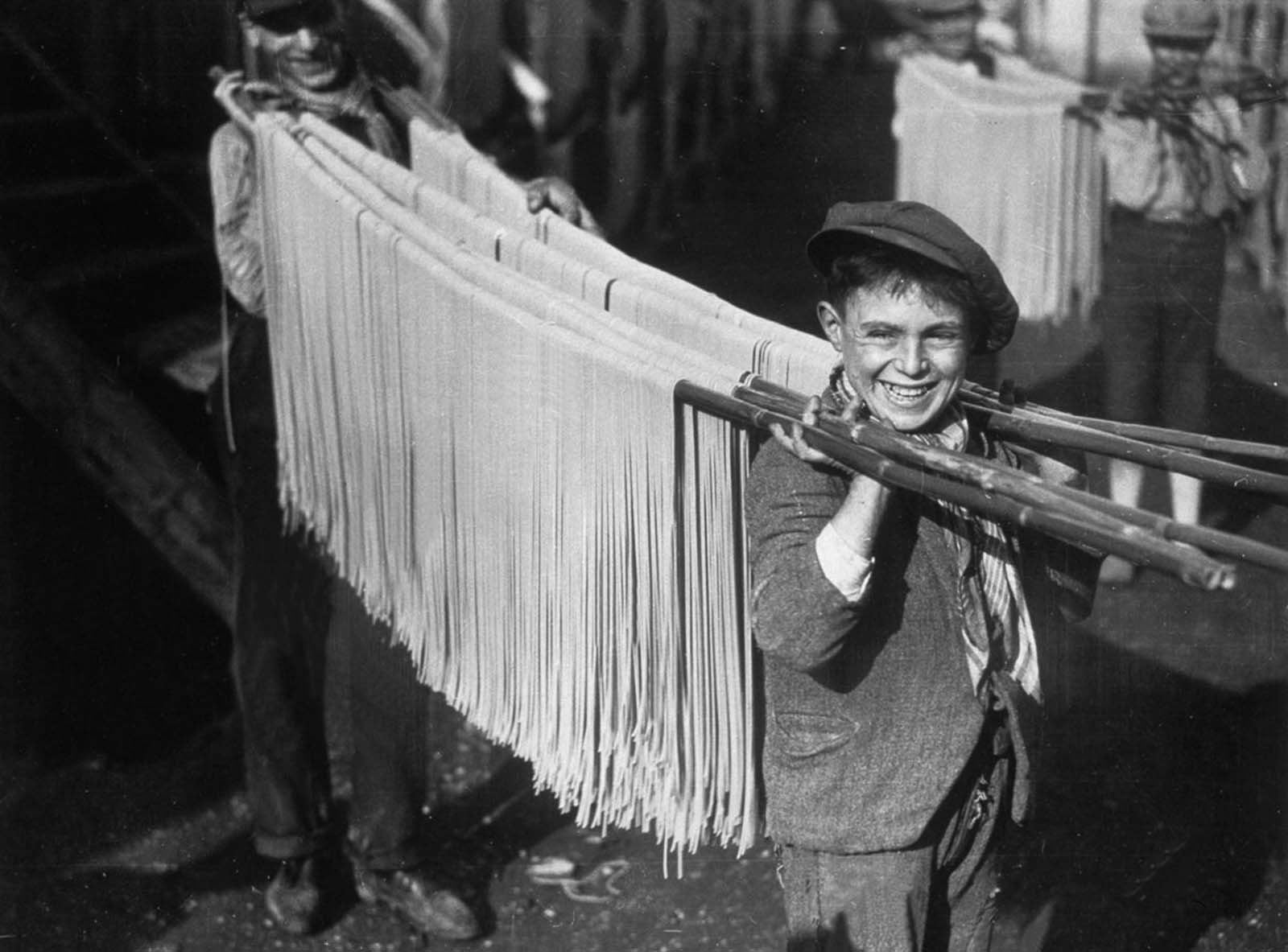 Freshly made pasta is carefully hung out to dry, a crucial step in the process. 1929.
