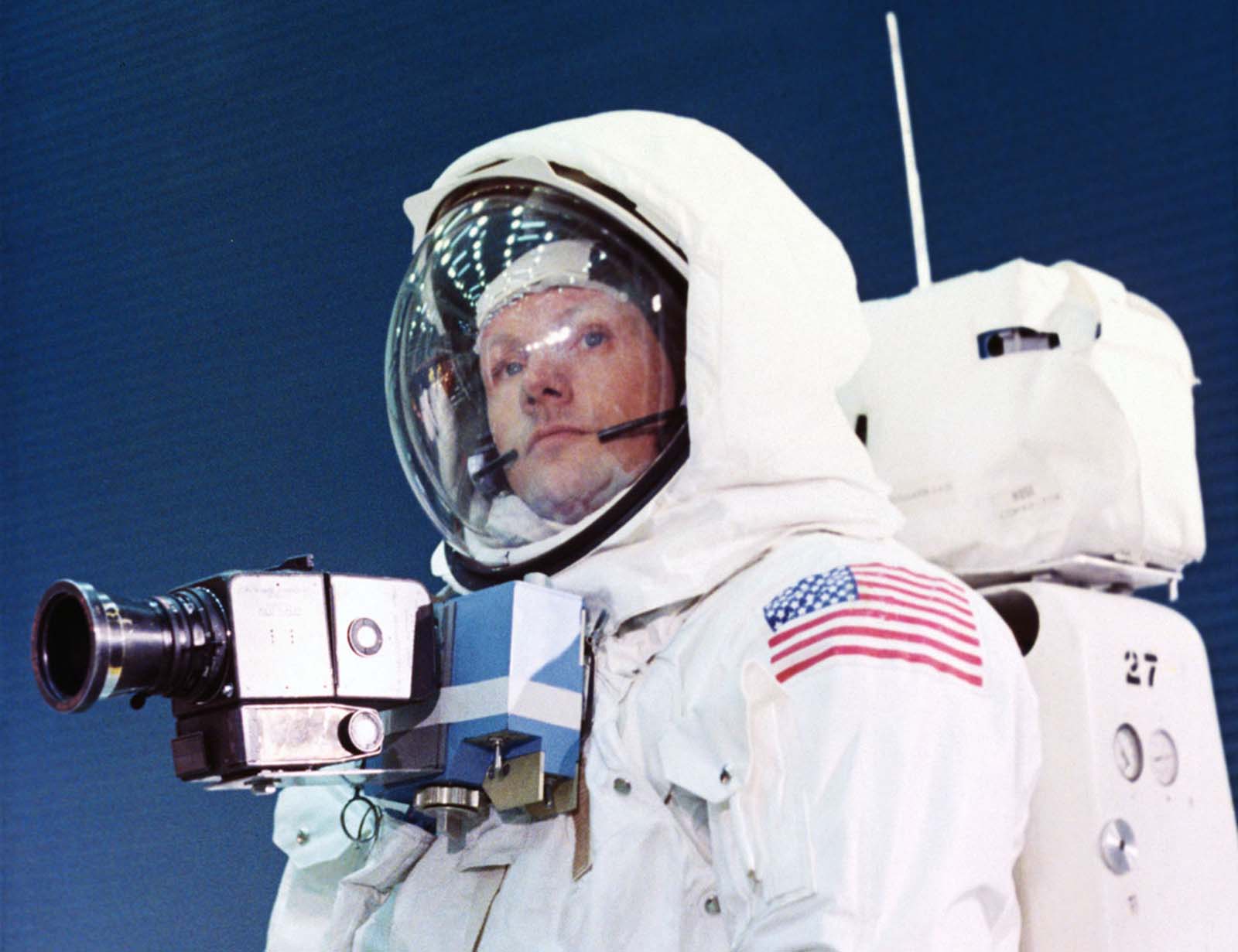 Fully suited and ready for lunar exploration, Neil Armstrong tests his spacesuit, complete with a chest-mounted camera and life-support backpack.