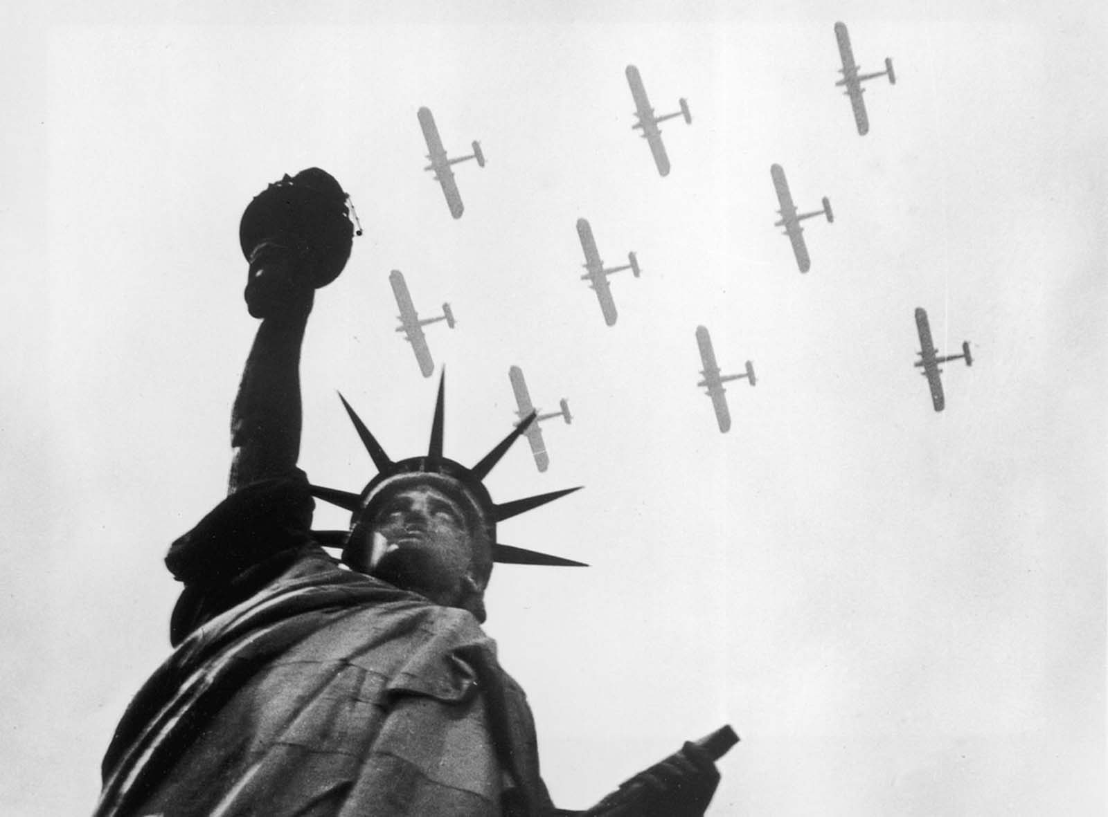 Military aircraft soar over the Statue of Liberty, symbolizing national strength and freedom, circa 1935.