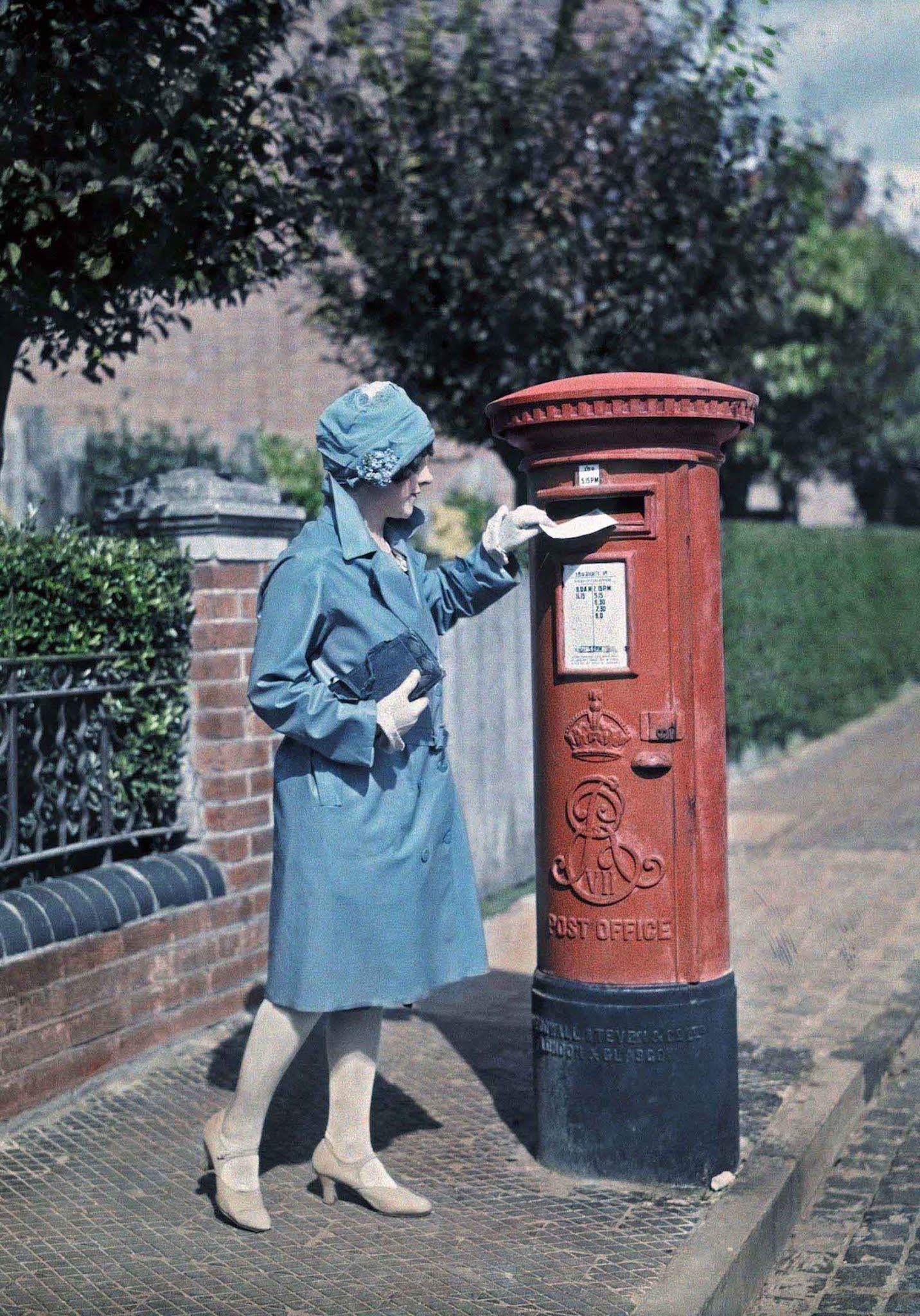 Sending a Letter in Oxford – A young woman carefully mails a letter at a traditional red pillar box.