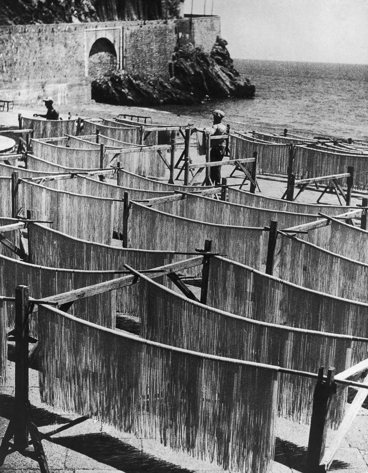Strands of spaghetti drying on racks near the shores of Amalfi, blending food and scenery. 1949.