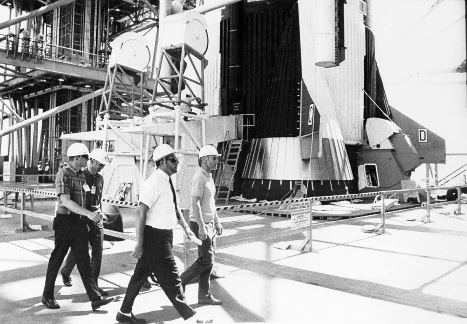 The Apollo 11 crew walks past the massive Saturn V rocket’s first stage during an emergency egress drill.