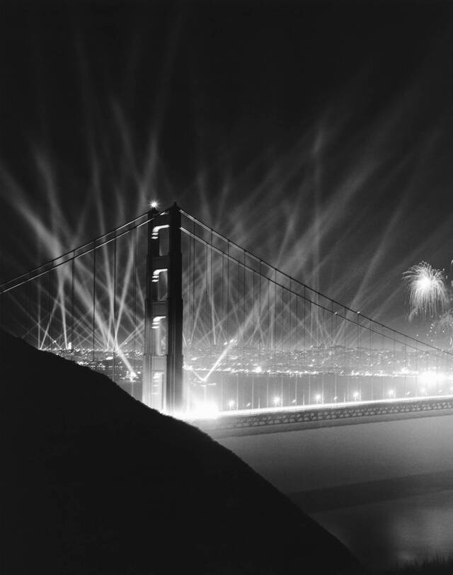 The night sky glows with the brilliance of Klieg lights and fireworks, creating a stunning backdrop for the majestic bridge. (Underwood Archives/Getty Images)