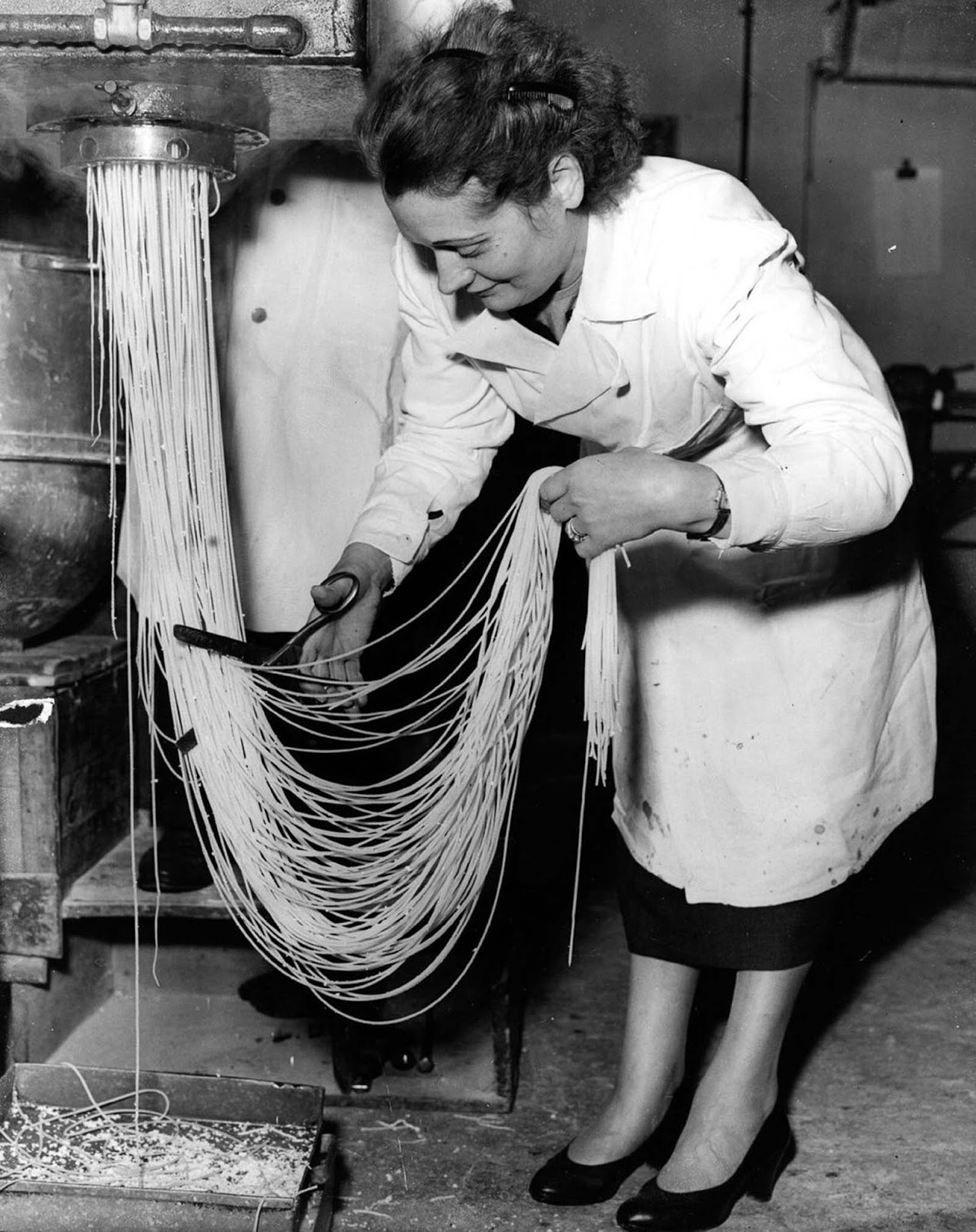 Zelda Albano cuts spaghetti into precise lengths as it emerges fresh from the machine. Holloway, London, 1955.