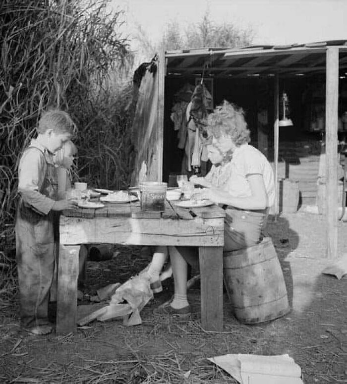 A Tennessee packinghouse worker with three of her four children enjoying supper—fried potatoes, cornbread, and canned milk—in Belle Glade, Florida.