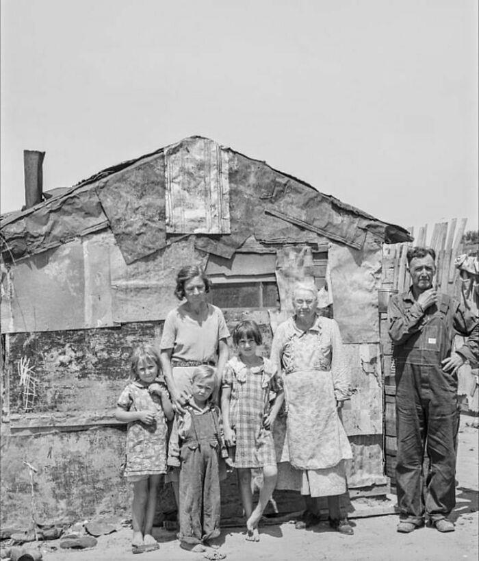 A family stands in front of their shack home at Mays Avenue Camp, Oklahoma City, Oklahoma.