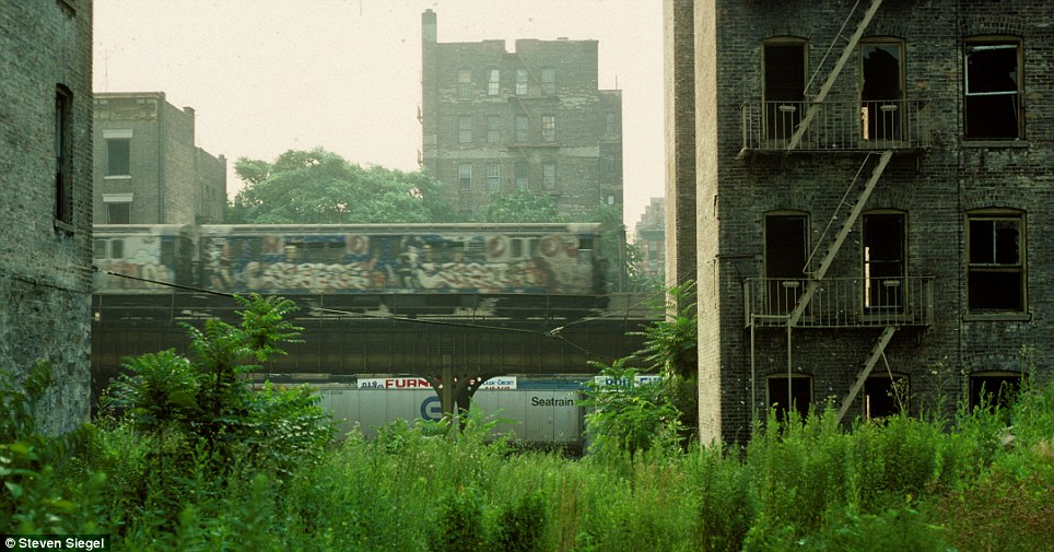 A fleeting moment captured as a graffiti-covered subway car speeds past between towering buildings, leaving a blur in its wake.