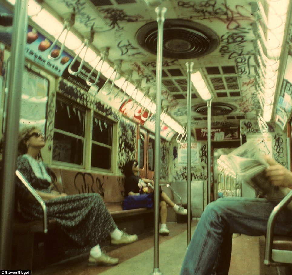 A throwback to the 1980s: two women, sunglasses on, riding in a subway car that’s heavily tagged with graffiti, embodying the spirit of the times.